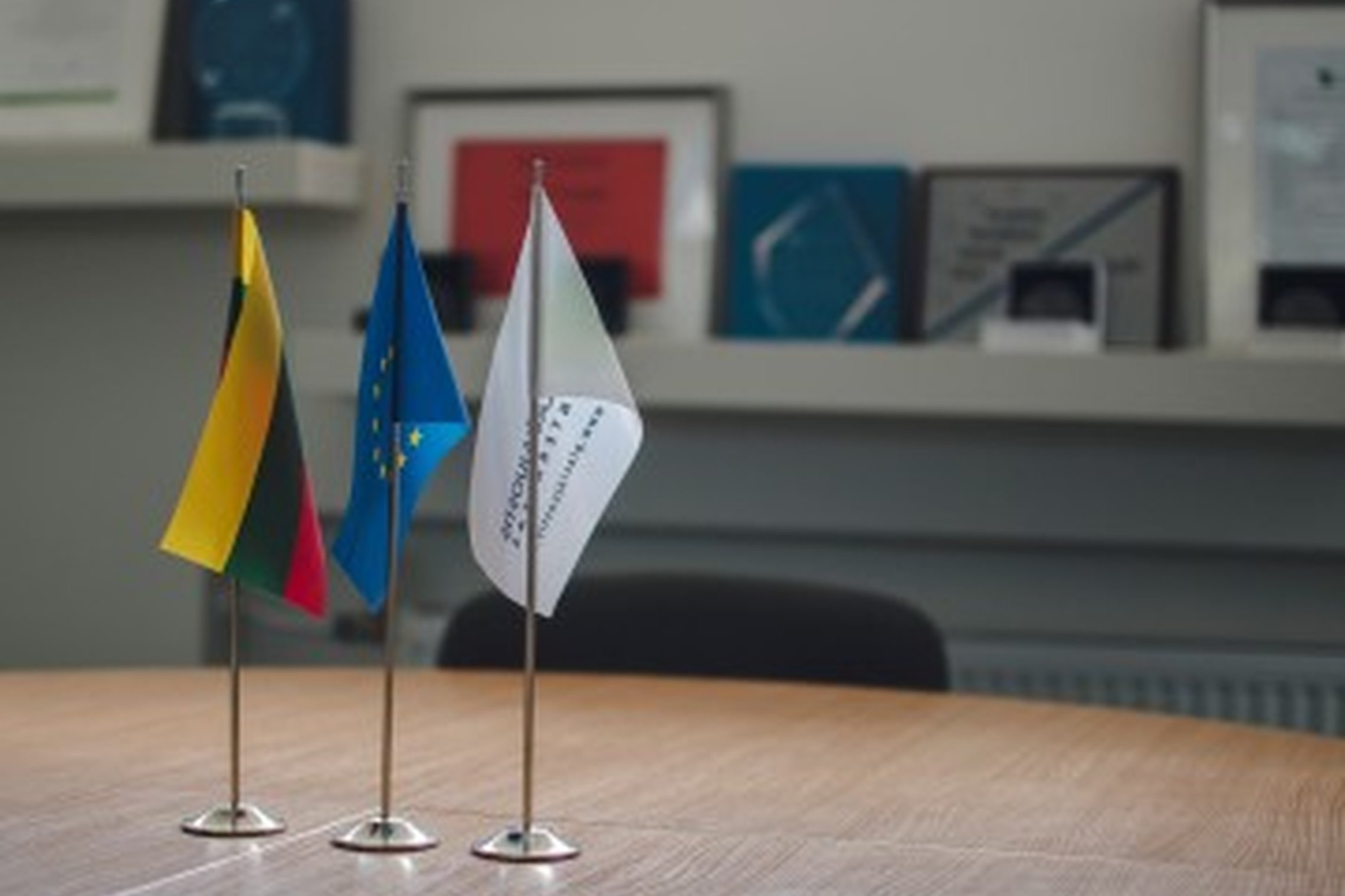 Stovinčios ant stalo Lietuvos, Europos Sąjungos vėliavos, vėliava su VšĮ „Plačiajuostis internetas" logotipu.
